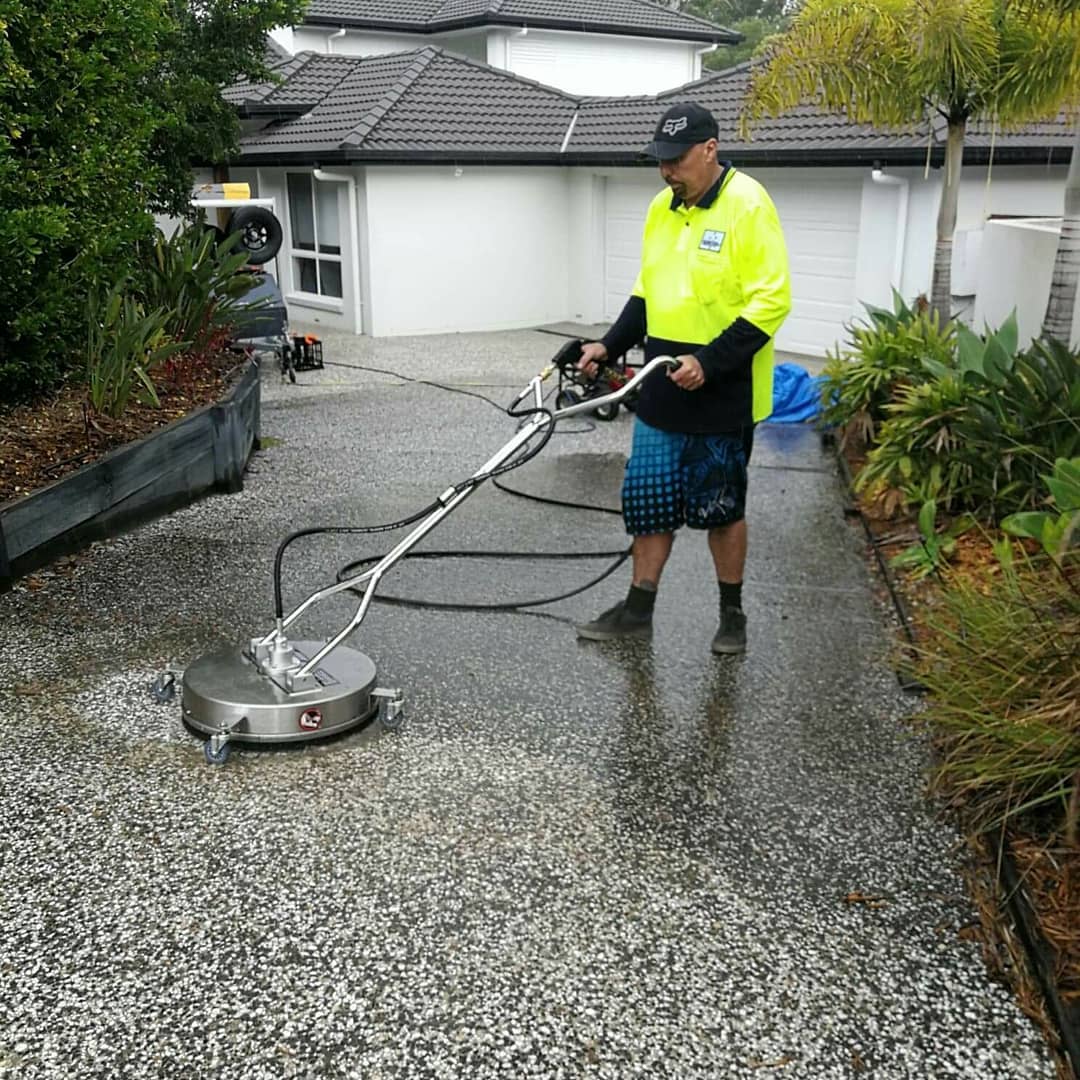 pressure washer using heavy duty pressure washing equipment to clean driveway